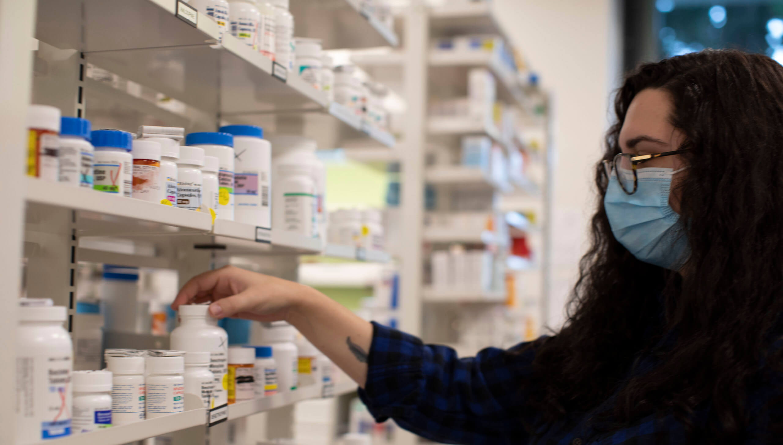 Pharmacy working grabbing a pill bottle