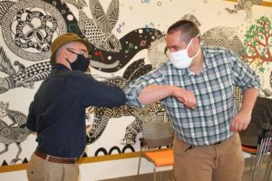Chris Wilhite, Major Gifts Officer, and Miles Sledd, Associate Director of Primary Care, greet each other with the new CCC handshake.