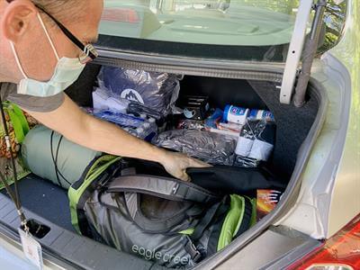 Man reaching for backpack in trunk of car