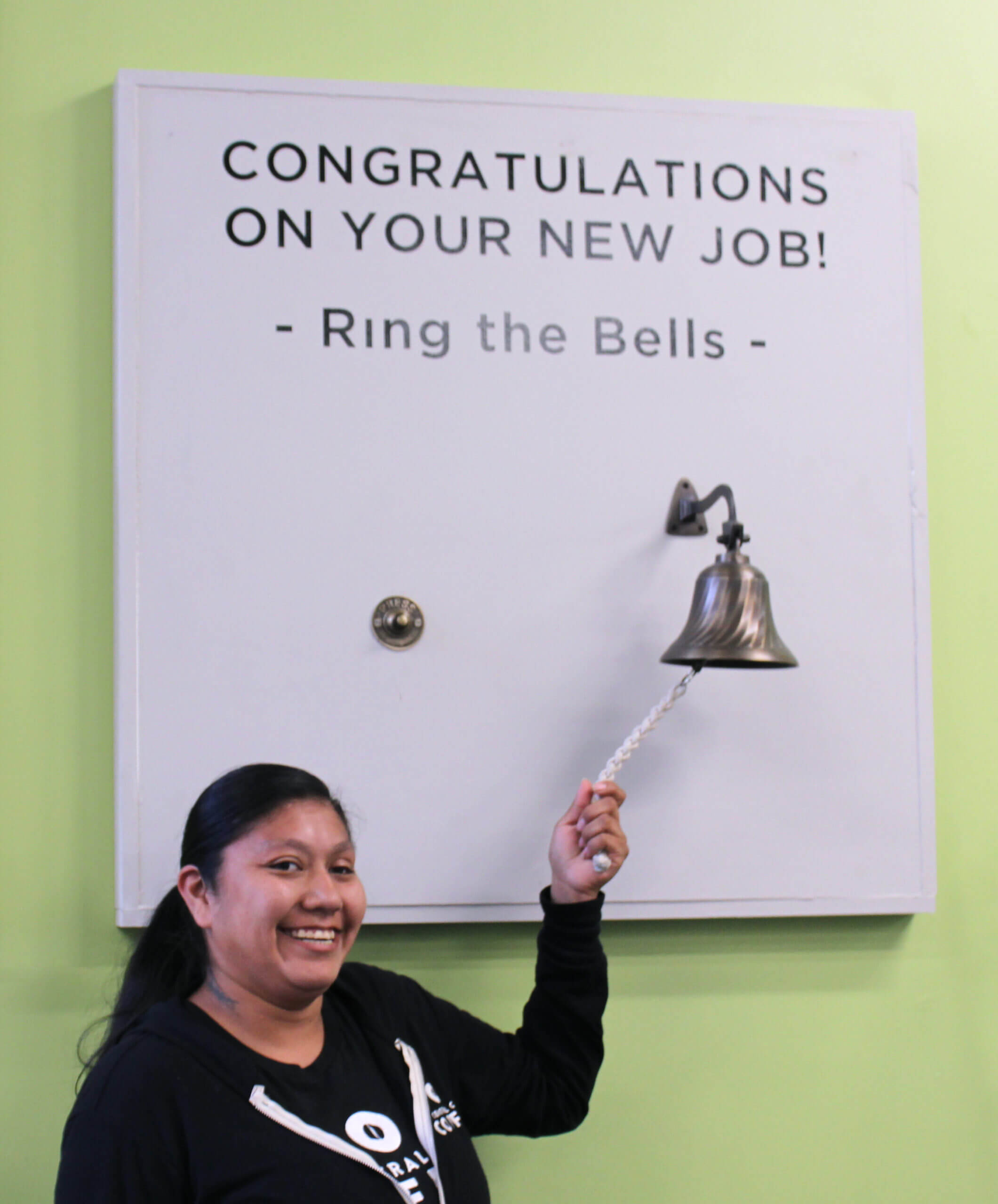 Woman ringing bell at employment access center after receiving a new job